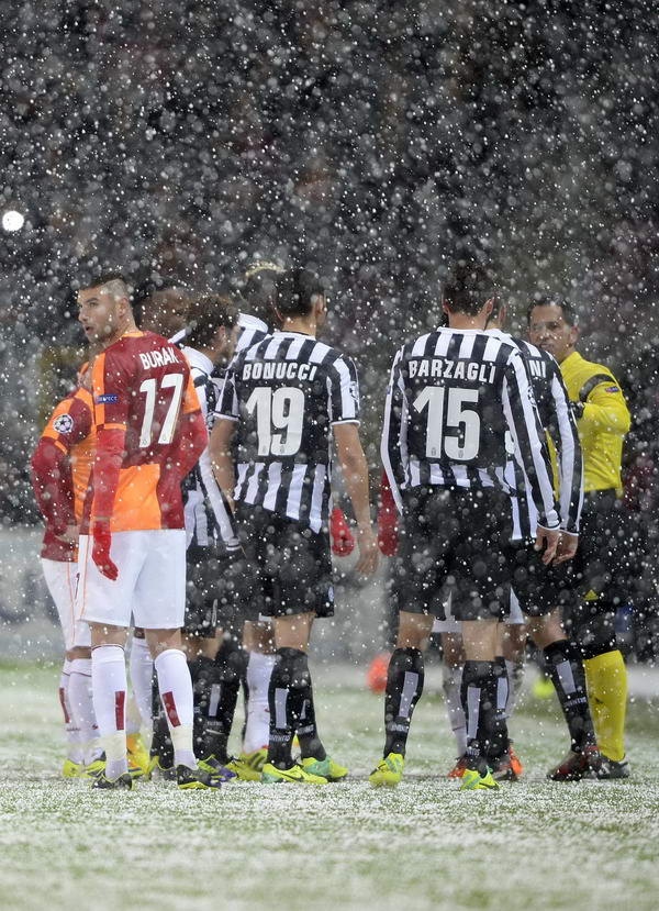 Galatasaray's and Juventus' players speak with referee Pedro Proenca after a heavy snow fall halted their UEFA Champions League group B football match at the TT Arena Stadium in Istanbul on December 30, 2013. AFP PHOTO/BULENT KILIC