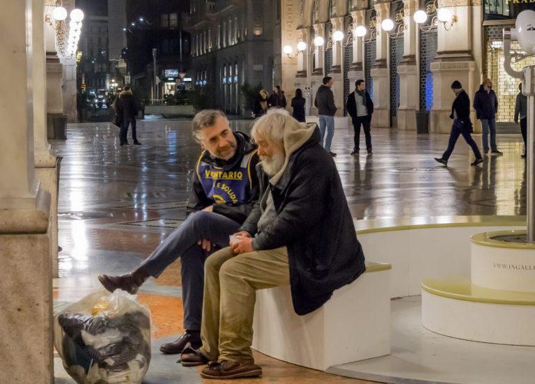 Un volontario dell’Associazione Ronda Carità e Solidarietà Milano con una persona senza dimora