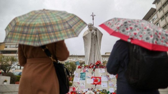 I fedeli sotto la statua di San Giovanni Paolo II a pregare per Papa Francesco